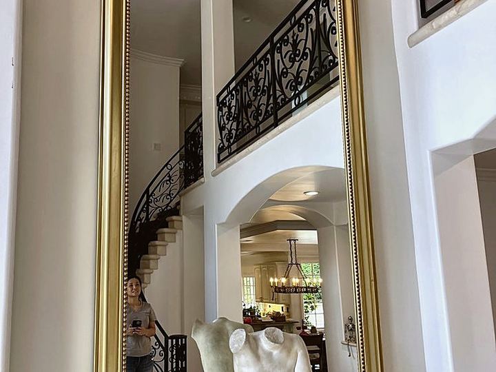 Tall gilded mirror hung securely in an entry hall