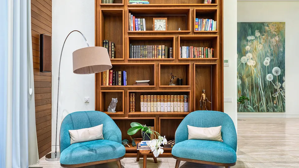 Tall wood bookcase behind two armchairs in a living room