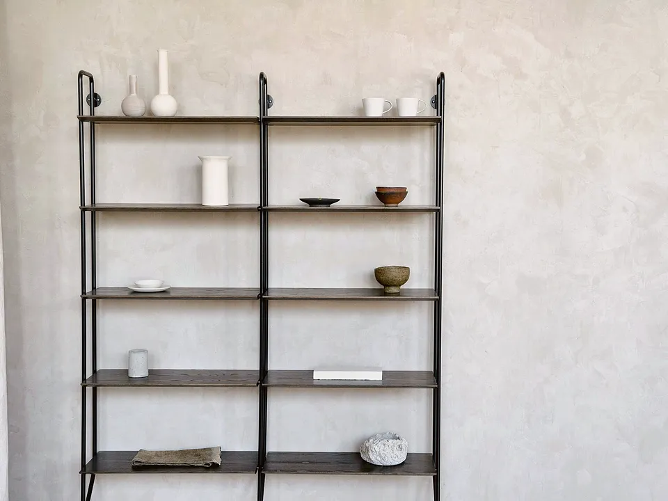 Tall open metal shelf standing against a wall