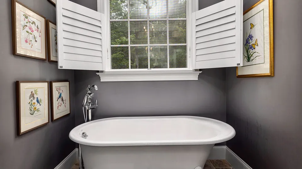Older-style bathroom with a clawfoot tub under a shuttered window