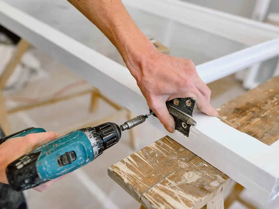 Drill driving a screw into a white cabinet frame