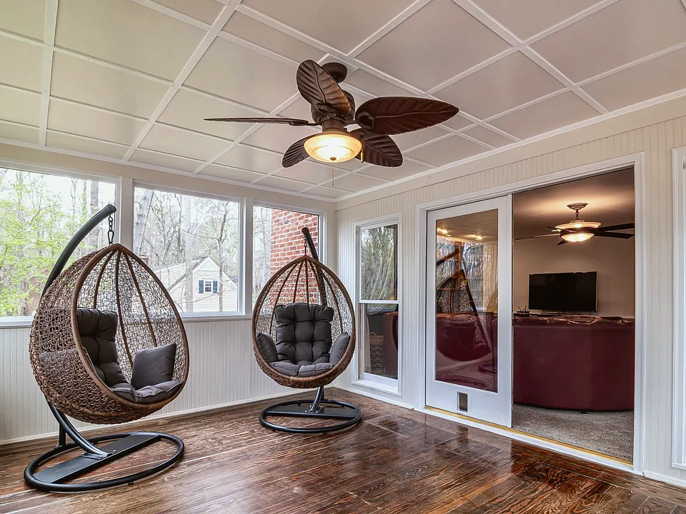Dark-bladed ceiling fan over a sunroom seating area