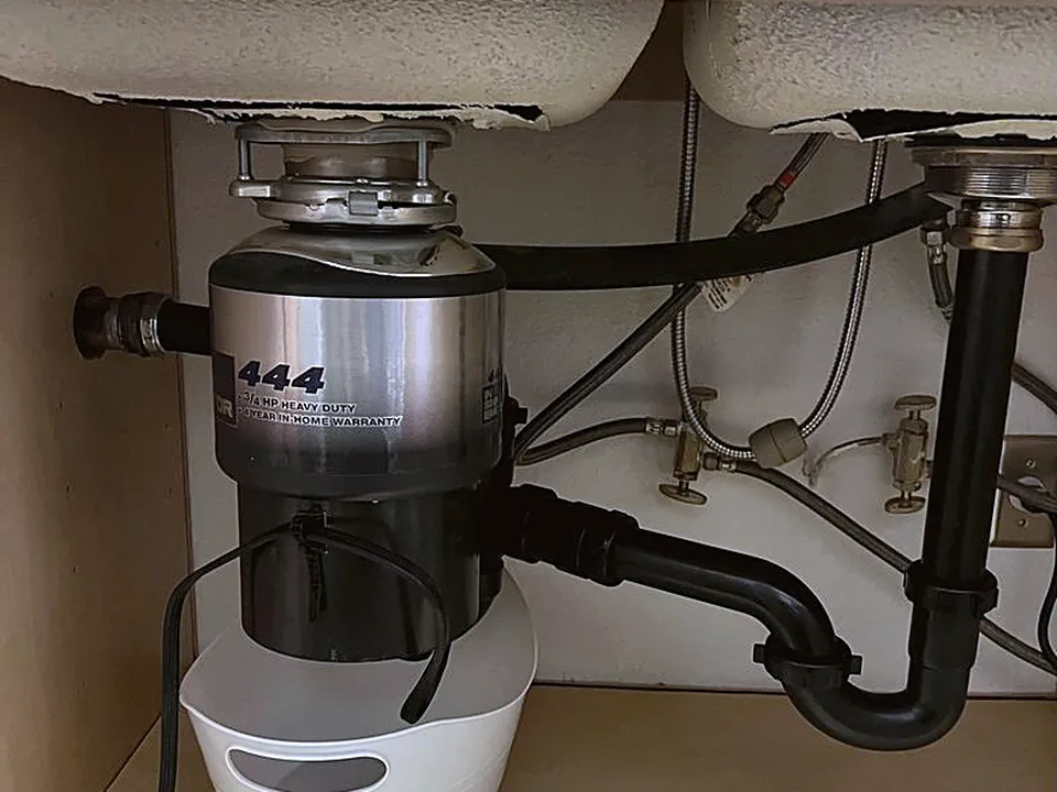 Garbage disposal connected to the drain under a kitchen sink