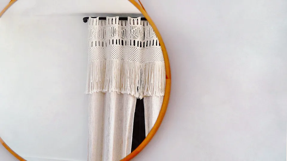 Round wood-framed mirror hanging on a white wall