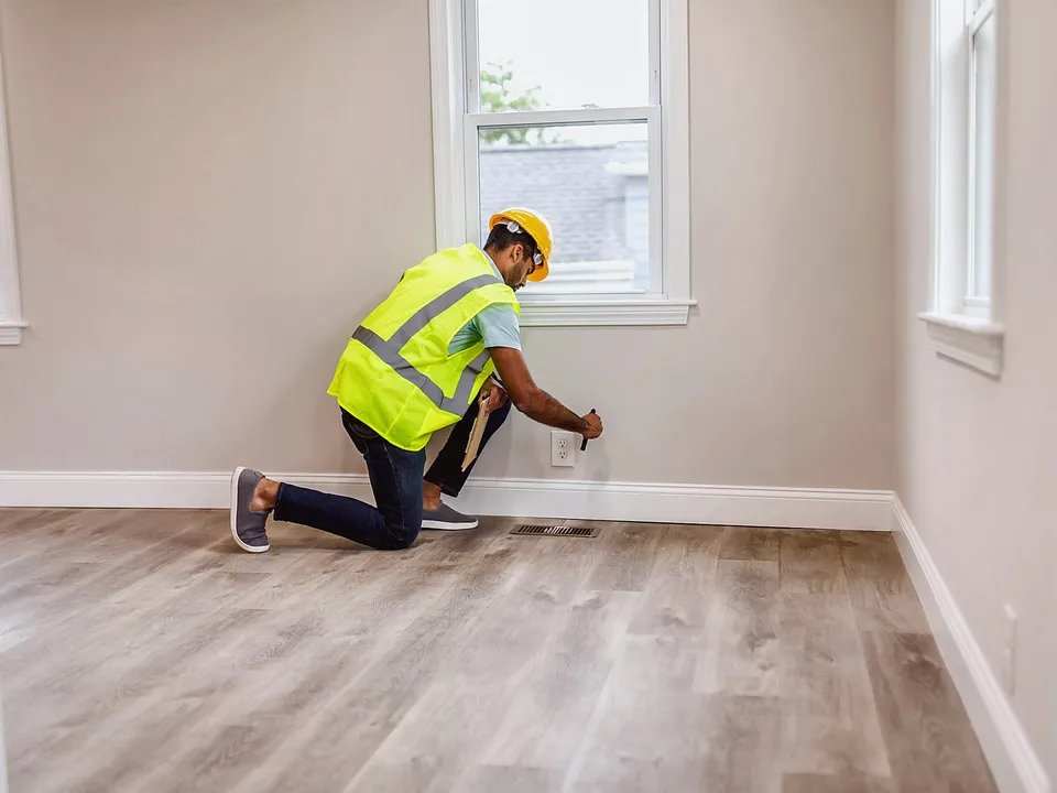 Inspector in a safety vest kneeling to test a wall outlet