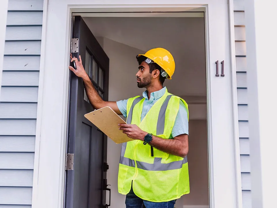 Inspector checking an exterior door frame with a clipboard in hand