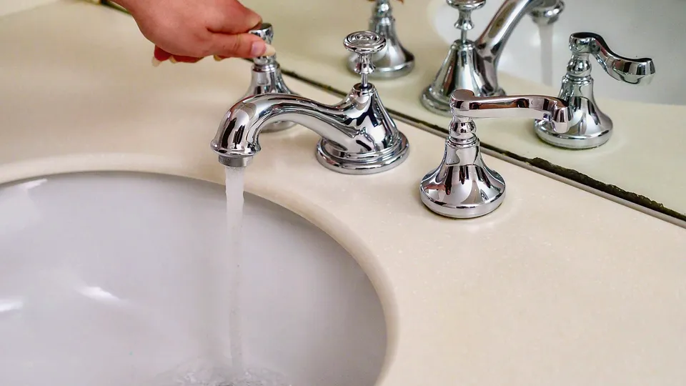 Hand turning on a two-handle bathroom faucet