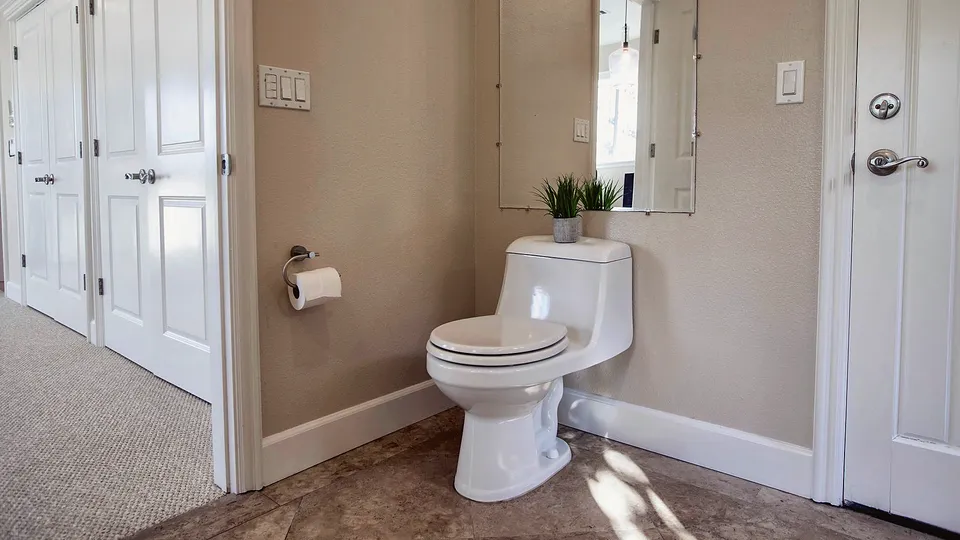 White toilet in a small bathroom with a tile floor