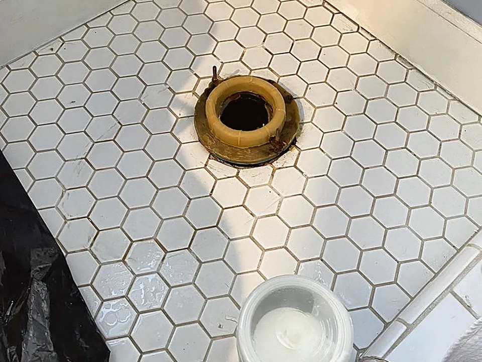 New wax ring set on the toilet flange in a white hex-tile floor