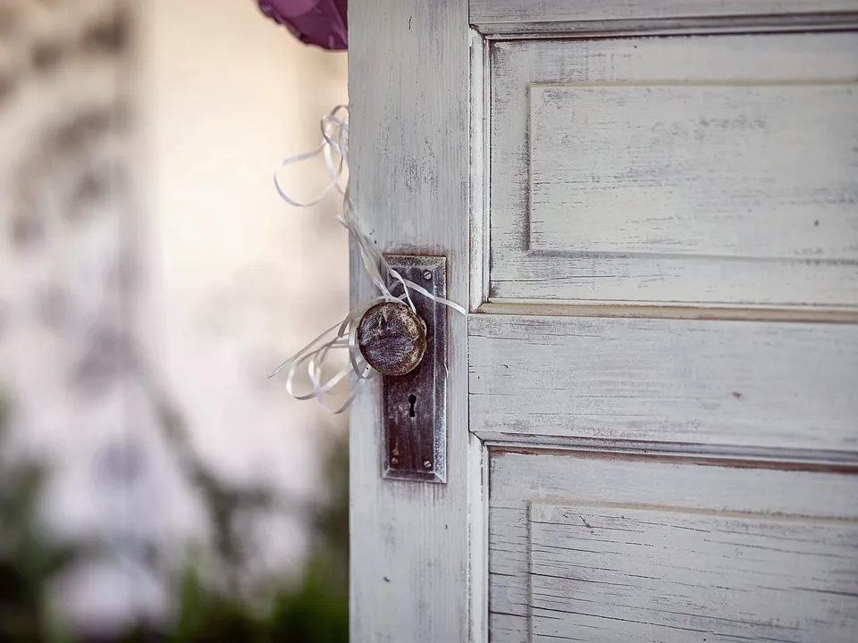 Old white paneled door with a worn knob