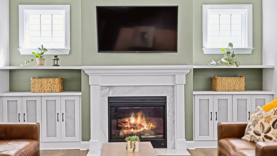 TV mounted above a white fireplace mantel between built-in shelves