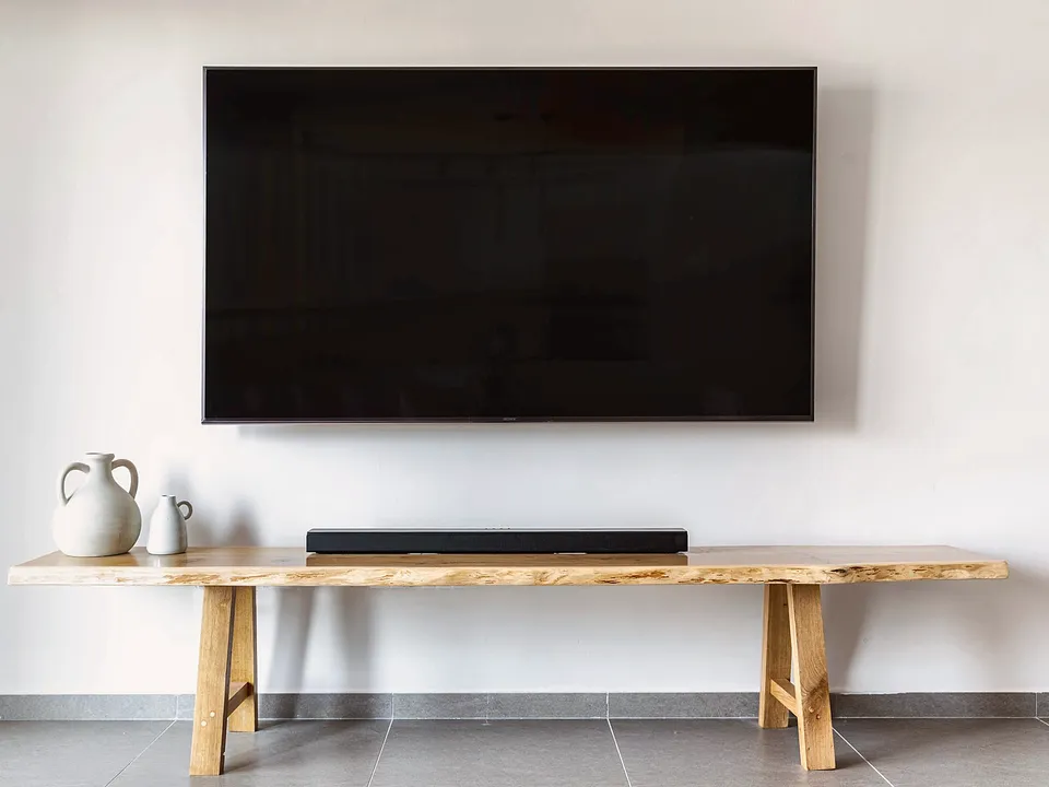 Flat-screen TV mounted on a white wall above a wood console