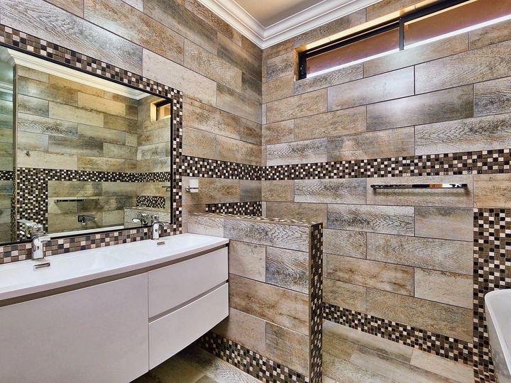 Bathroom with a long vanity mirror, tiled walls and ceiling lighting