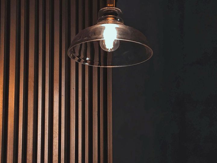 Glass pendant light hanging against a dark slatted wall