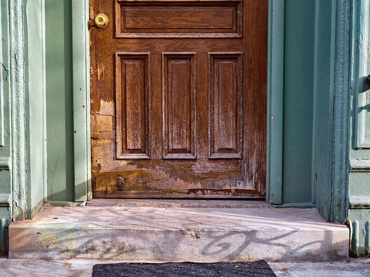 Weathered wood front door above a worn concrete step
