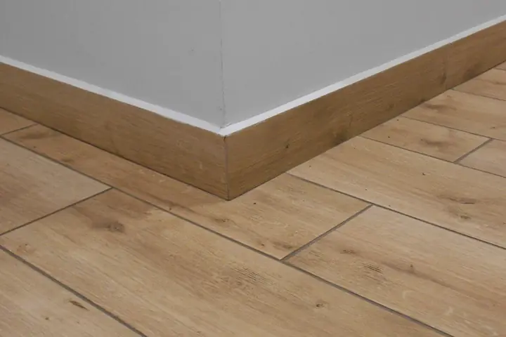 Baseboard meeting a wood floor at an outside corner