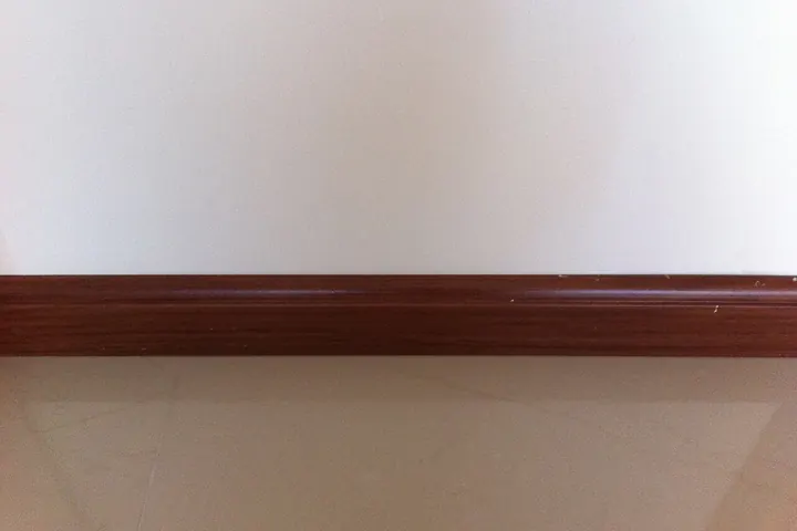 Dark wood baseboard against a pale painted wall