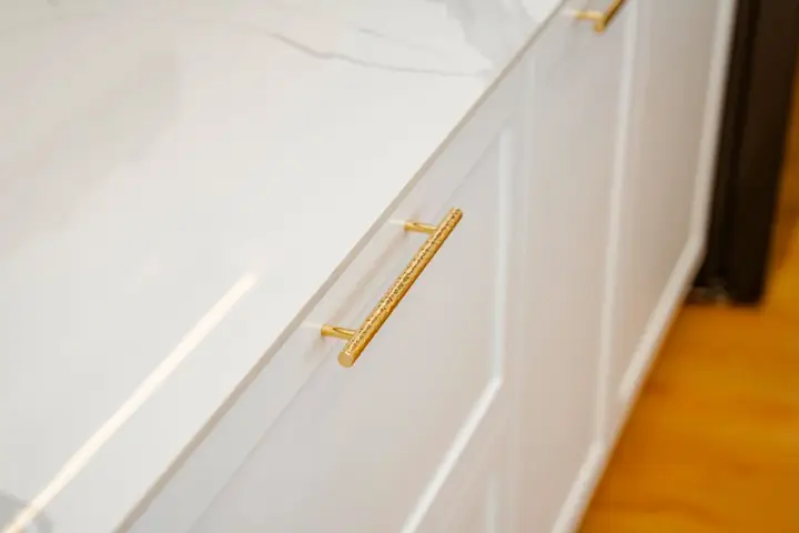 Sophisticated white cabinet with gold handles and marble top