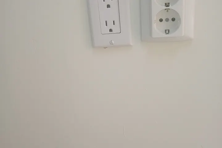 Two white duplex outlets on a pale wall