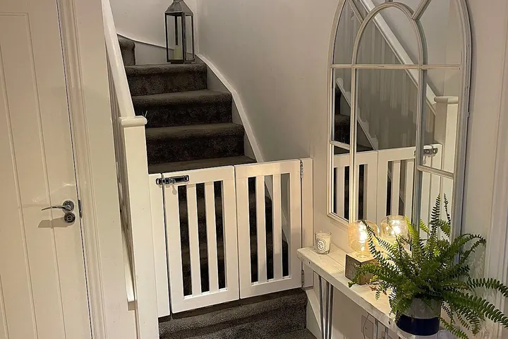 White wooden safety gate across the bottom of a carpeted staircase