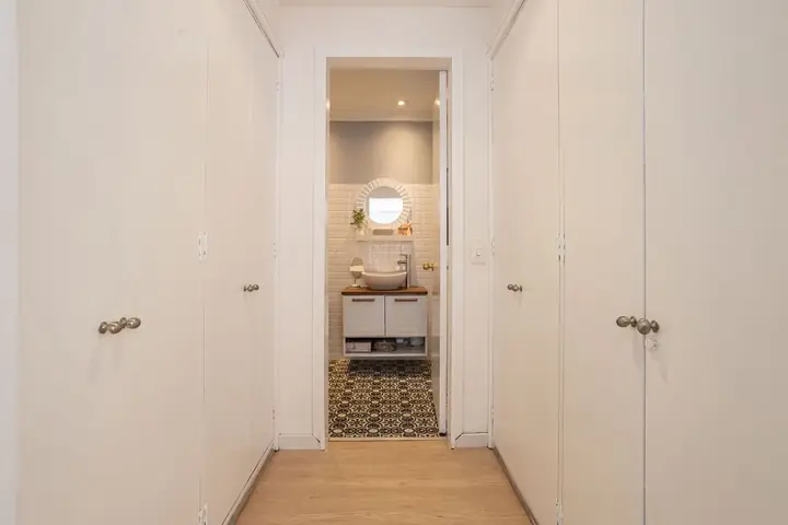 Narrow hallway lined with white closet doors and round knobs