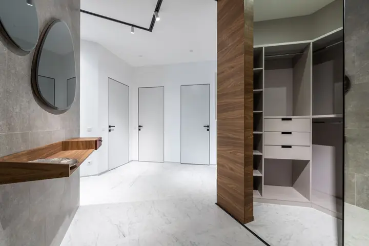 White hallway with a mirror, closet doors and open wardrobe