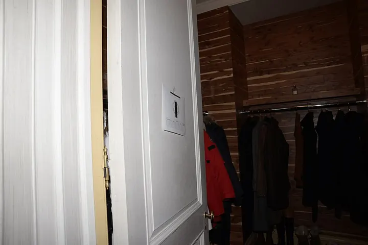 Open closet door with hanging clothes