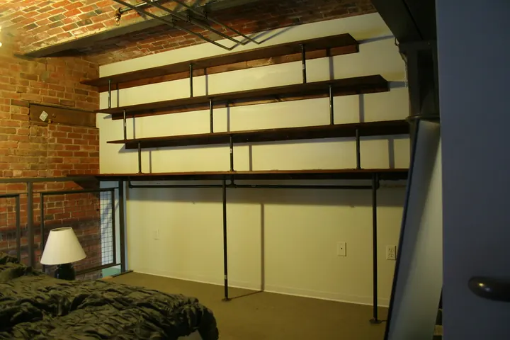 Wall-mounted shelves on metal rails above a bedroom