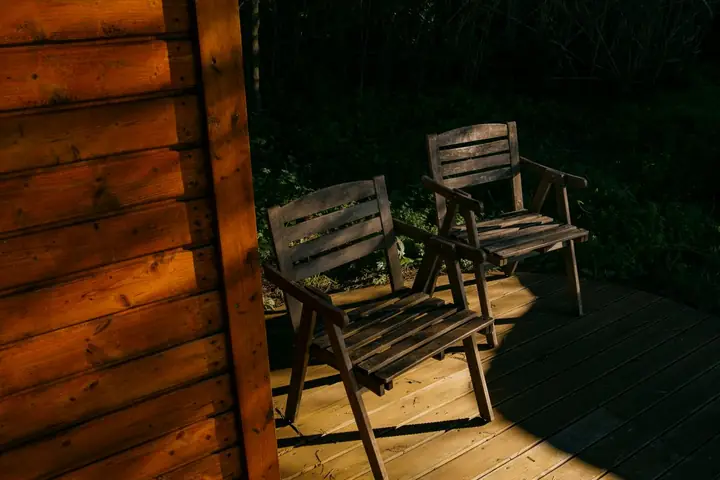 Wood chairs on a deck at night beside a wood cabin