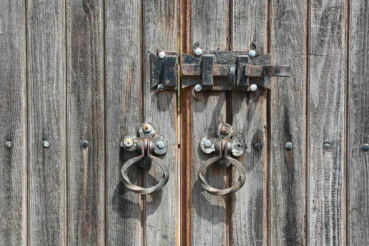 Iron slide bolt and ring pulls on a weathered plank door