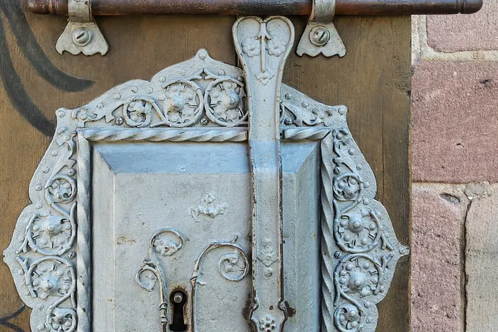 Ornate metal lock plate with a slide bolt above