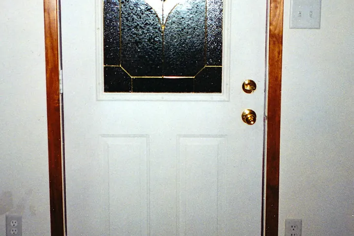 White exterior door with a glass insert and brass knob