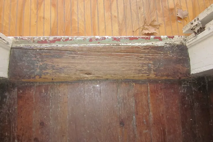 Worn wood door sill at the base of an old doorway