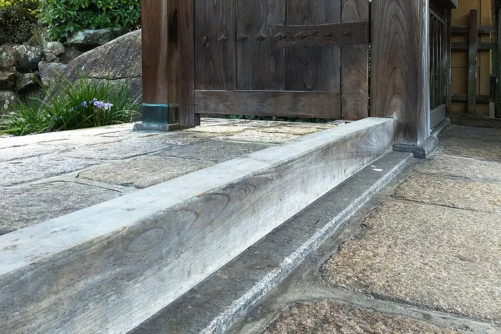 Weathered wooden threshold at the base of an old gate