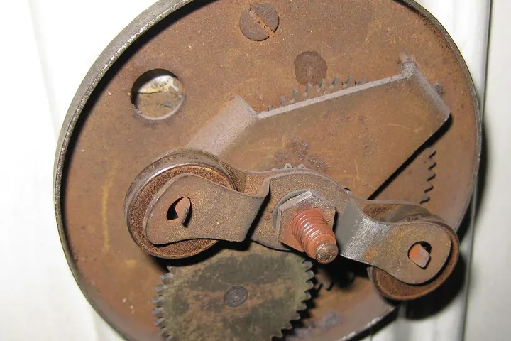 Inside of an old mechanical doorbell with rusty gears