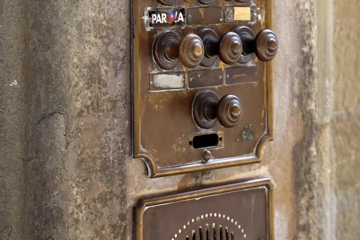 Old intercom panel with brass buttons and a speaker