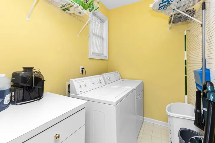 Laundry room with washer, dryer, and shelves in bright setting