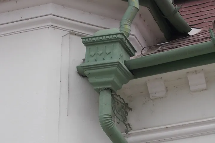 Gutter and downspout bending around a cornice