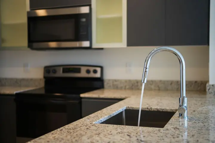 Water running from a pull-down faucet into a granite counter sink