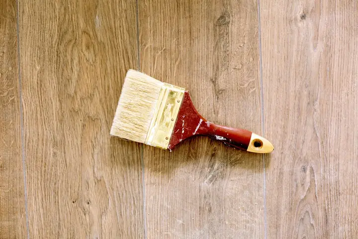 An used paintbrush lying on a wooden floor