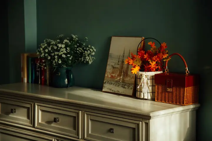 Dresser with floral decor and artwork in warm autumn colors