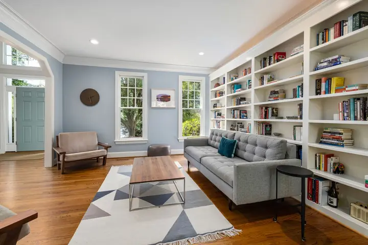 Living room with a gray sofa and a tall white bookshelf wall