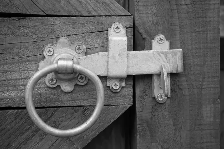 Metal ring latch on a weathered gray wood gate