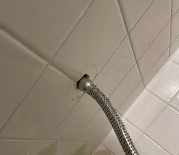 Braided steel supply hose running from the tiled wall to a fixture