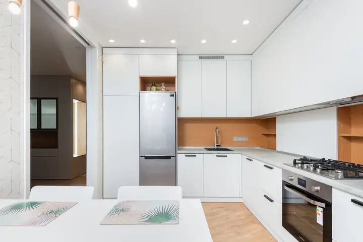 White kitchen with a tall refrigerator and gas cooktop