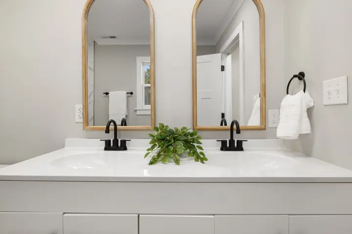 Two arched mirrors above a white double vanity