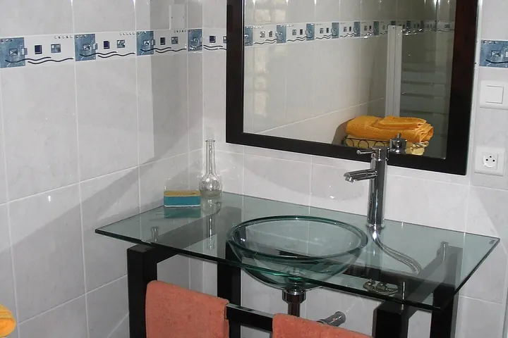 Glass vanity with a framed mirror and orange towels