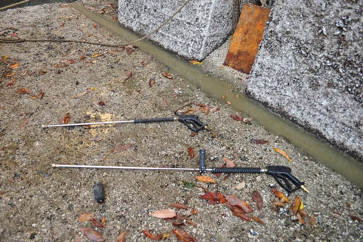 Pressure washer wand and hose lying on a dirt yard