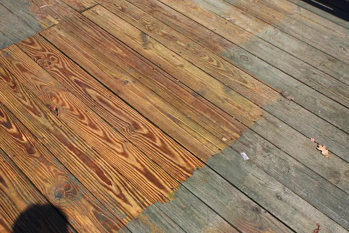 Wood deck boards half cleaned, showing fresh grain beside gray weathered wood