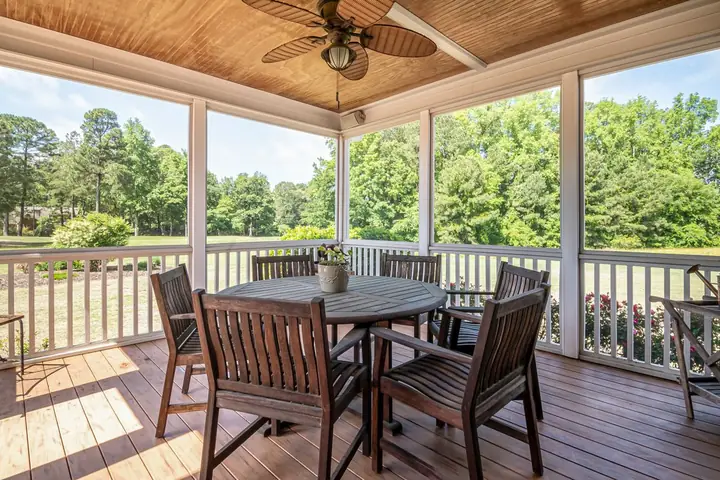Covered porch with a ceiling fan, wood table and chairs